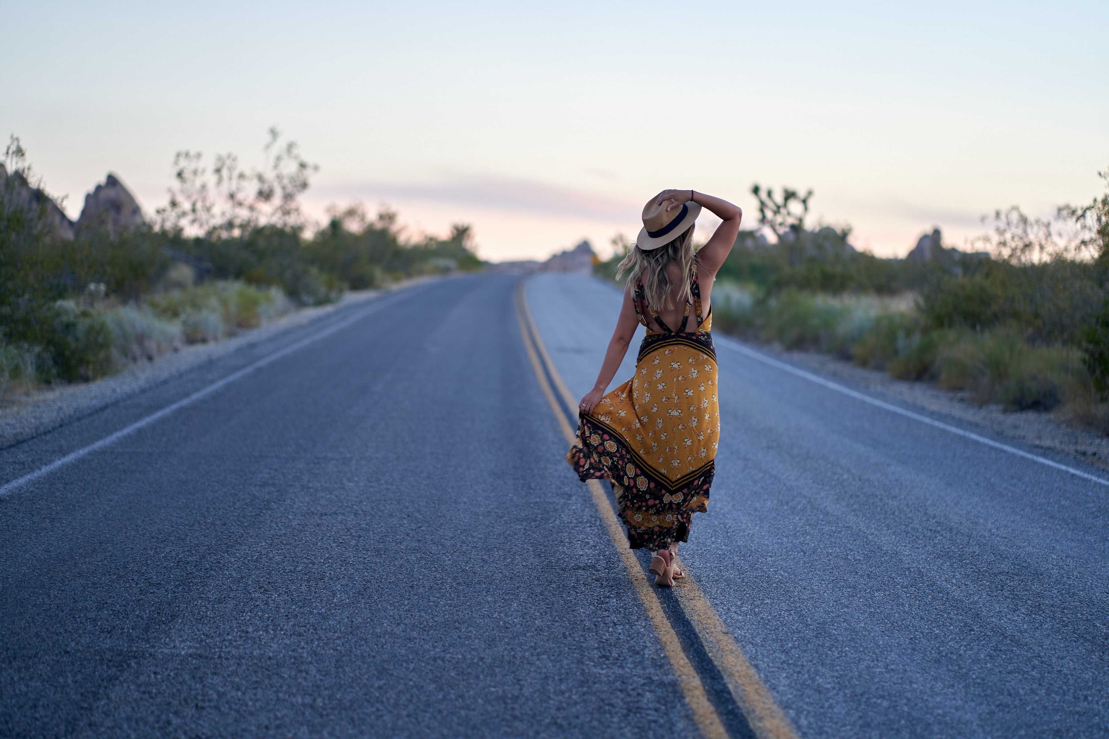 A pretty woman wearing stylish clothes walking along an outstretched road